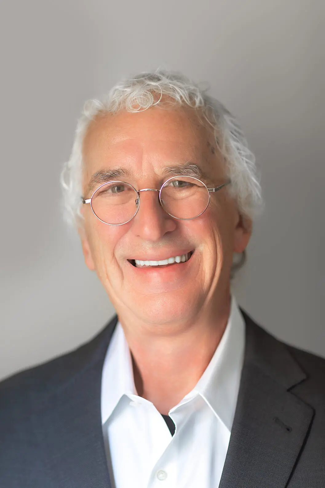 Smiling man with glasses and white hair.
