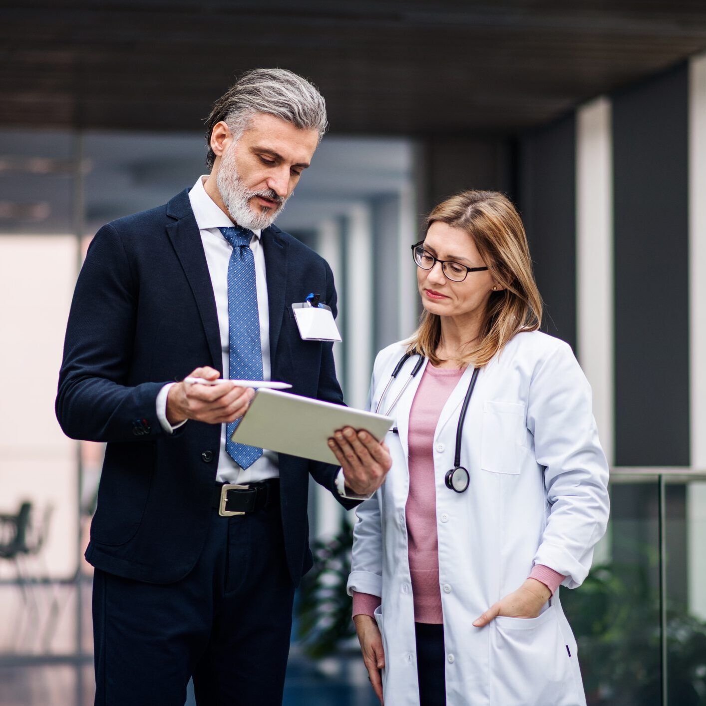 Doctor and businessman discussing documents in hallway.