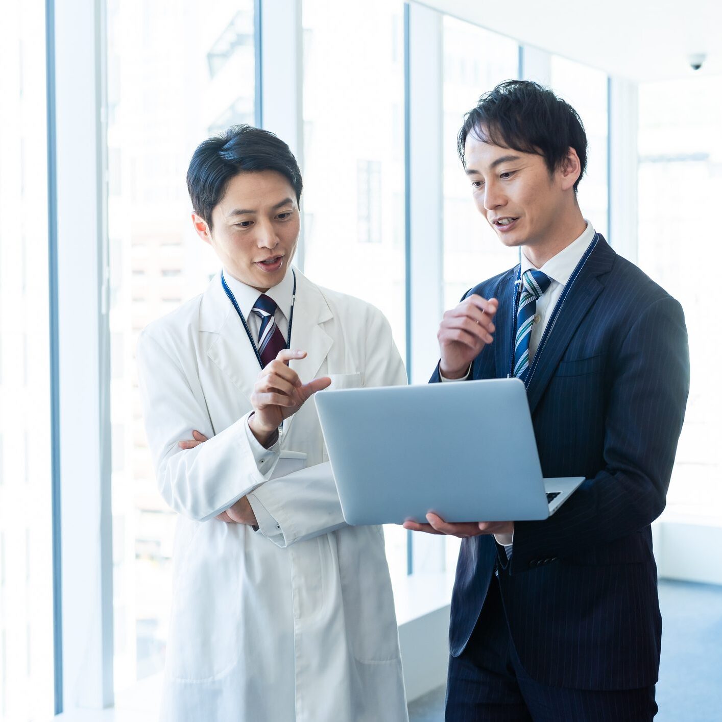 Doctor and businessman discussing over laptop.
