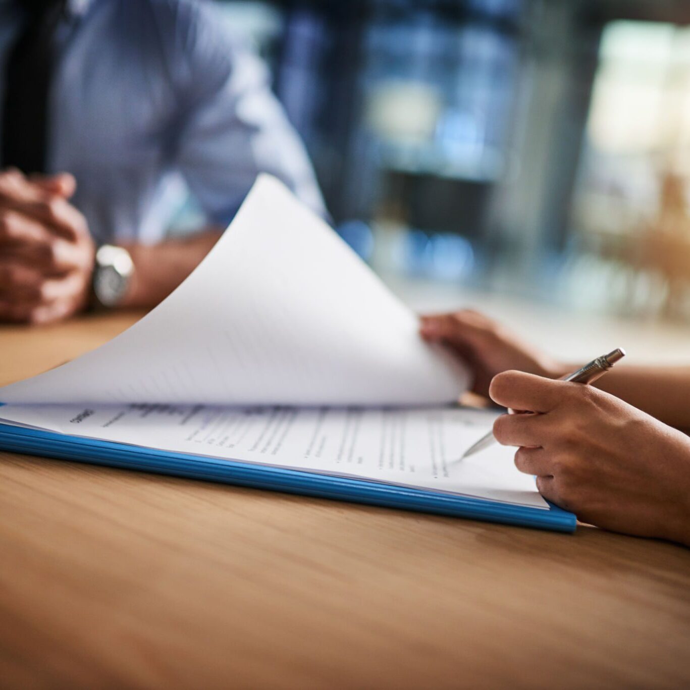 Hands reviewing documents at a meeting table.
